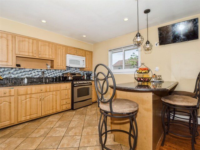 915 Derrick Adkins Ln, West Hempstead, NY 11552 - kitchen featuring white microwave, stainless steel range with gas cooktop, a breakfast bar area, decorative backsplash, and light brown cabinetry