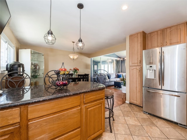 915 Derrick Adkins Ln, West Hempstead, NY 11552 - kitchen featuring stainless steel fridge with ice dispenser, light tile patterned floors, dark stone counters, and a breakfast bar area