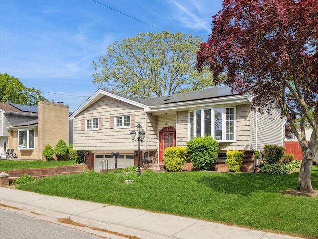 915 Derrick Adkins Ln, West Hempstead, NY 11552 - bi-level home featuring roof mounted solar panels, a front lawn, an attached garage, and brick siding