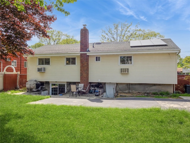 915 Derrick Adkins Ln, West Hempstead, NY 11552 - back of house featuring roof mounted solar panels, a chimney, a patio, a wall mounted air conditioner, and a shingled roof