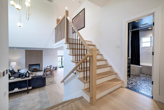 64 Jane Ct, Westbury, NY 11590 - staircase featuring a high ceiling, wood finished floors, and a fireplace