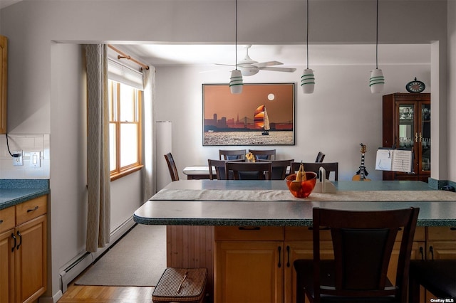 dining room with baseboard heating, a ceiling fan, and light wood-style flooring