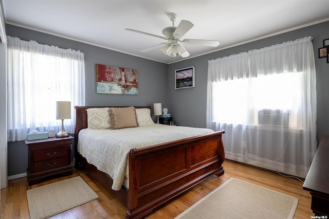 bedroom featuring ornamental molding, light wood-type flooring, and a ceiling fan
