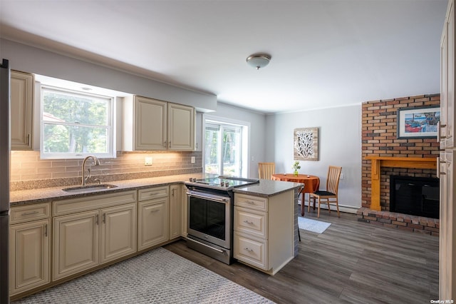 kitchen featuring a fireplace, stainless steel electric range oven, a sink, and cream cabinetry