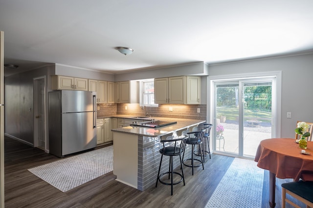 kitchen with freestanding refrigerator, a sink, plenty of natural light, and cream cabinets