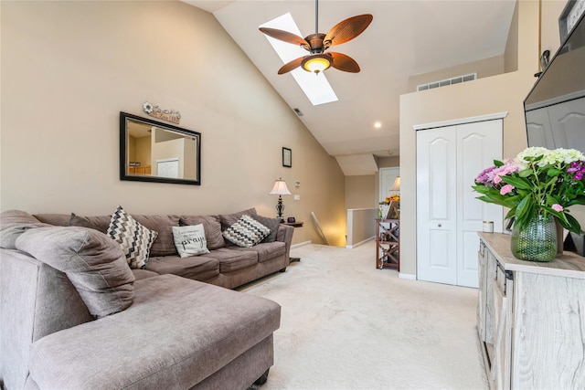 living area with a skylight, a ceiling fan, high vaulted ceiling, and light colored carpet