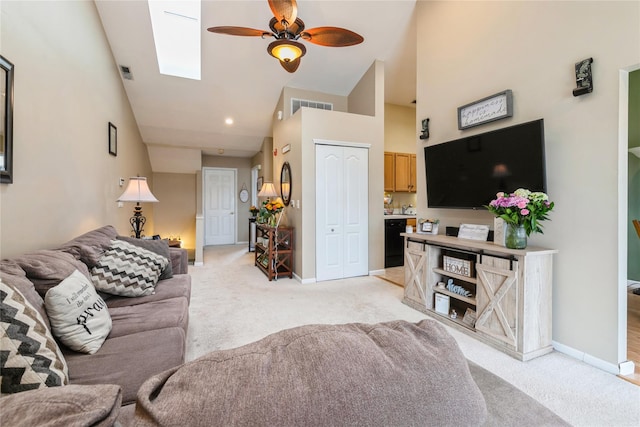 living area featuring light carpet, a ceiling fan, visible vents, and a skylight