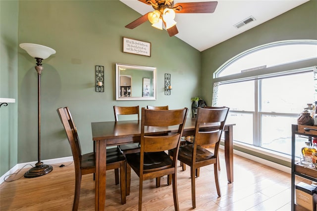 dining room featuring light wood-style floors, lofted ceiling, visible vents, and ceiling fan