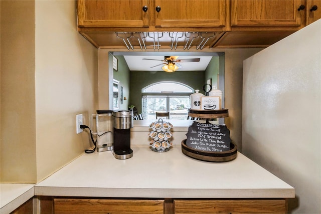 interior details with ceiling fan, brown cabinets, and light countertops