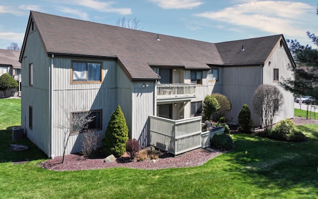 back of house with a lawn, roof with shingles, central AC, and a balcony