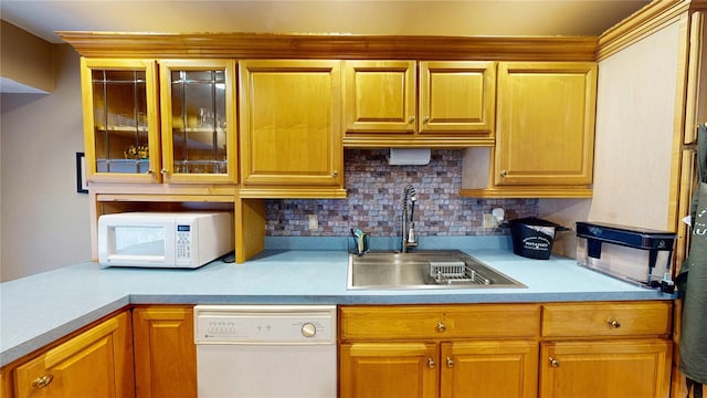 kitchen featuring a sink, decorative backsplash, white appliances, and light countertops