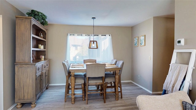 dining space with baseboards and light wood-style flooring