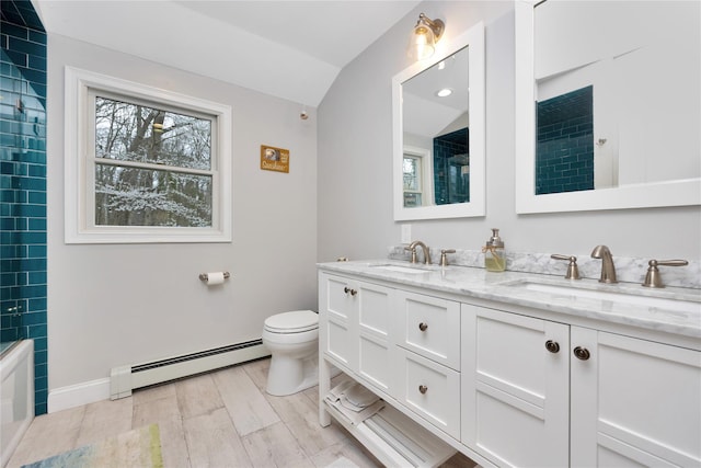 bathroom featuring baseboard heating, toilet, a sink, and double vanity