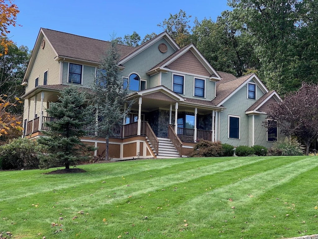 view of front of home featuring a front lawn, stairs, a porch, and a shingled roof