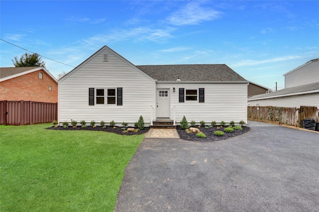 view of front of home featuring a front yard, entry steps, fence, and a shingled roof