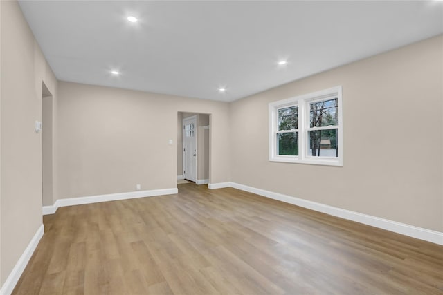 empty room with baseboards, recessed lighting, and light wood-style floors