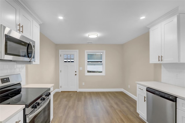 kitchen featuring tasteful backsplash, white cabinets, light countertops, light wood-style floors, and stainless steel appliances