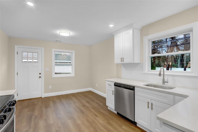 kitchen featuring light countertops, light wood-type flooring, appliances with stainless steel finishes, and a sink