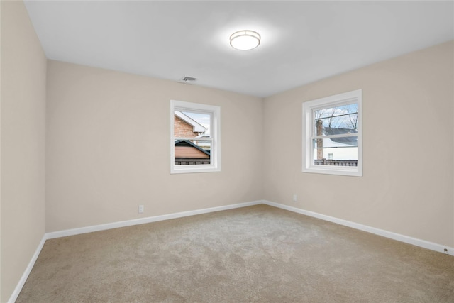 carpeted spare room with visible vents and baseboards