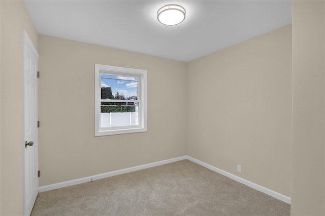 unfurnished room with baseboards and light colored carpet