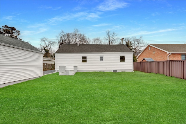 back of property featuring a yard, roof with shingles, and fence private yard
