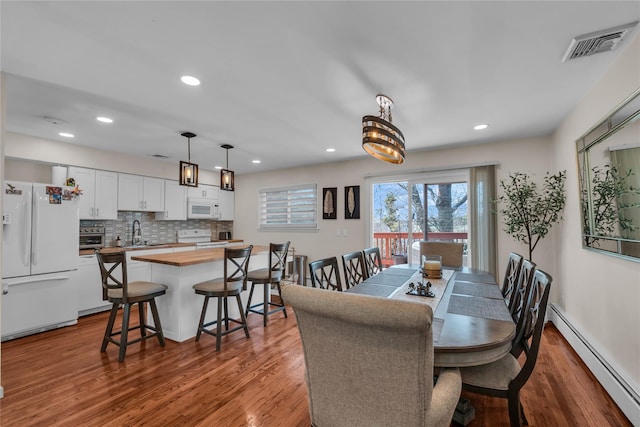 dining area featuring recessed lighting, visible vents, wood finished floors, and a baseboard radiator