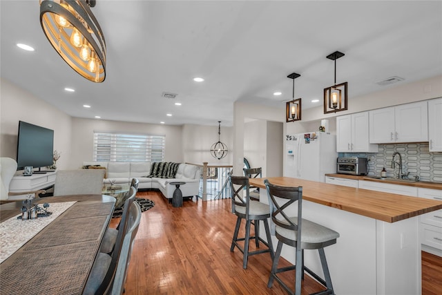 kitchen with white refrigerator with ice dispenser, a sink, wood counters, and visible vents
