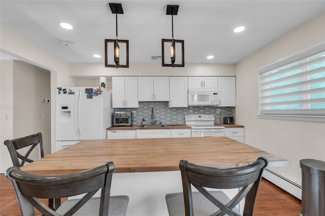 kitchen featuring white cabinetry, a baseboard radiator, a breakfast bar, wooden counters, and white appliances
