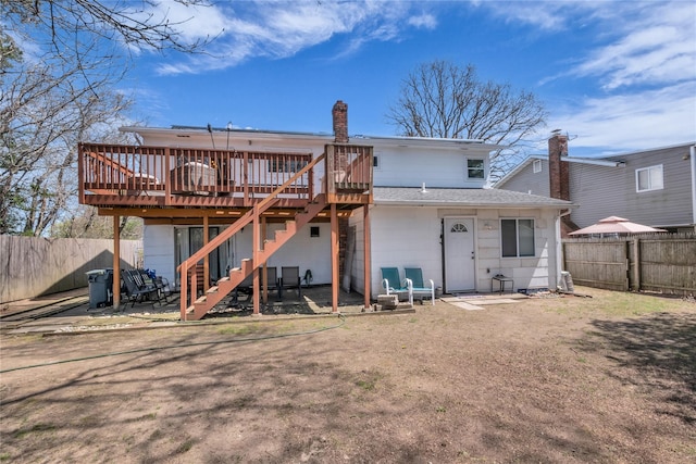 back of house with a chimney, stairway, a wooden deck, and a fenced backyard