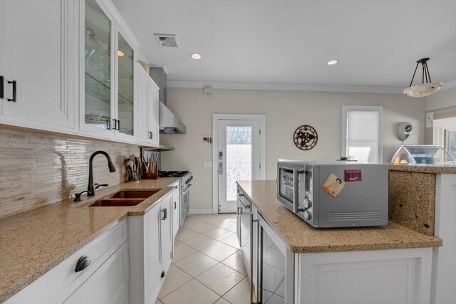 kitchen featuring a sink, light tile patterned flooring, stainless steel appliances, backsplash, and wall chimney exhaust hood