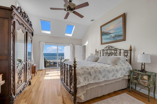 bedroom featuring access to exterior, visible vents, light wood-style floors, vaulted ceiling with skylight, and ceiling fan