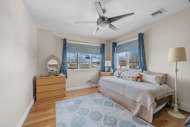 bedroom with baseboards, a ceiling fan, wood finished floors, and visible vents