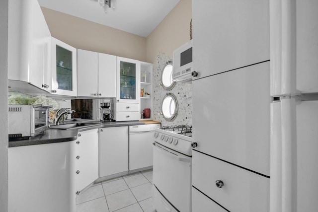 kitchen with dark countertops, a sink, white appliances, a toaster, and white cabinets