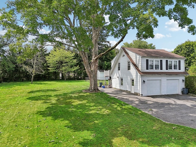 view of side of home featuring a garage, a yard, and aphalt driveway