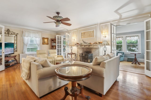 living room featuring a ceiling fan, wood finished floors, a wealth of natural light, and a fireplace