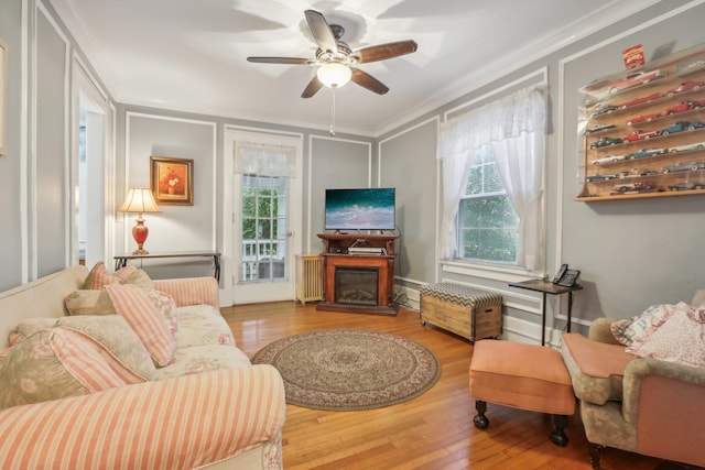 living area with ceiling fan, wood-type flooring, and a wealth of natural light