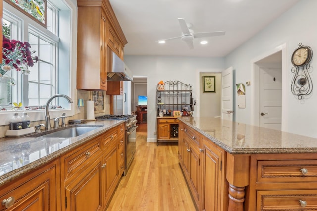 kitchen featuring light wood-style floors, a sink, high end range, and brown cabinets