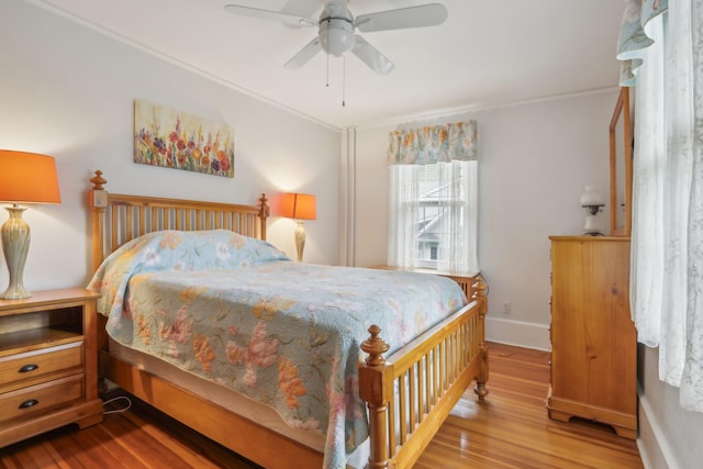 bedroom with baseboards, ornamental molding, a ceiling fan, and wood finished floors