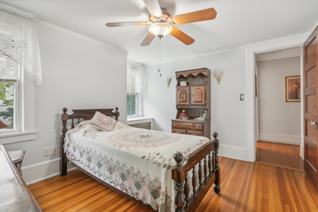 bedroom with crown molding, baseboards, a ceiling fan, and light wood-type flooring