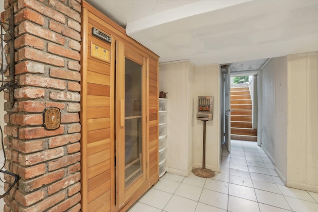 hallway featuring baseboards, light tile patterned flooring, and stairway