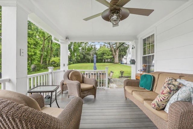 wooden terrace with a lawn, covered porch, and ceiling fan