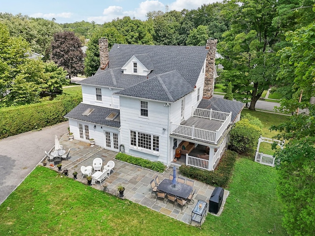 back of property with french doors, a chimney, a lawn, a patio area, and a shingled roof
