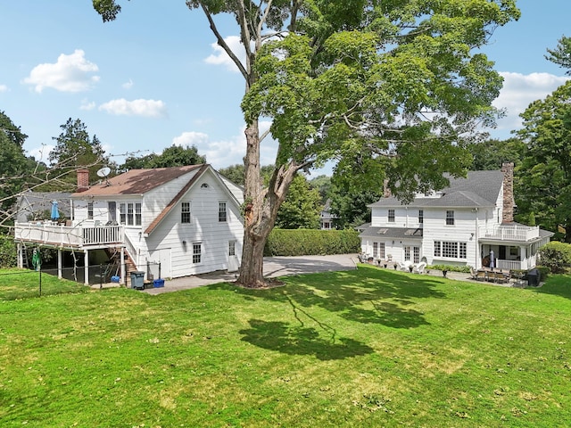 back of property featuring a lawn, a wooden deck, a patio area, and stairway