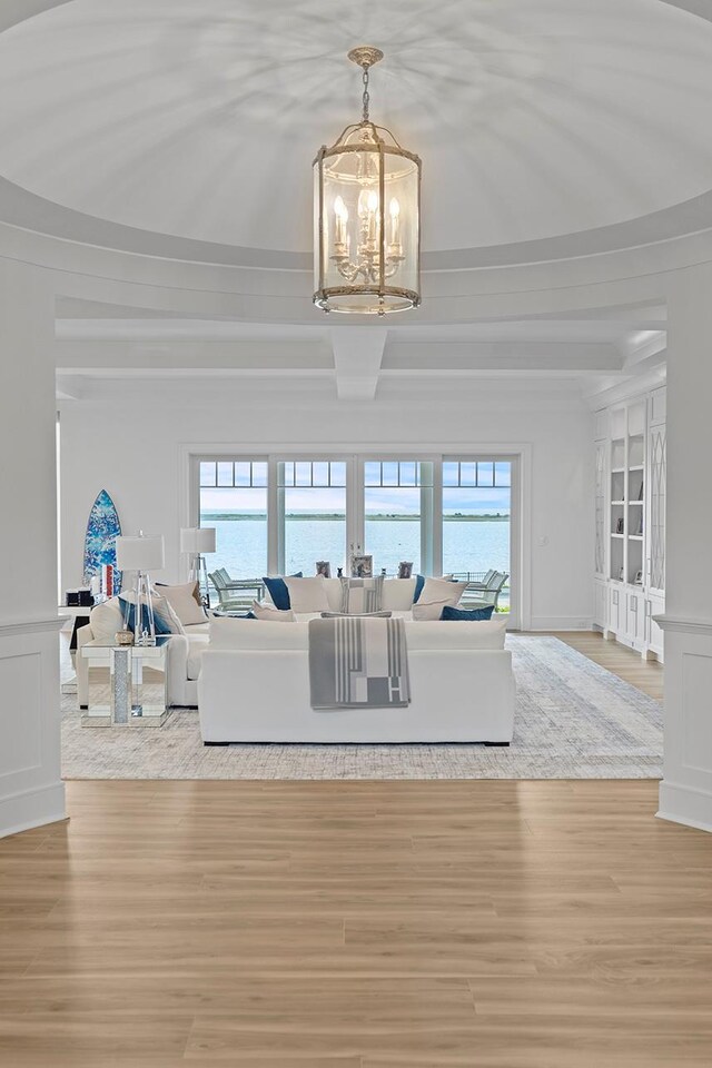 25 Brewster Ln, East Setauket, NY 11733 - living room featuring a chandelier, a decorative wall, healthy amount of natural light, and light wood-style flooring