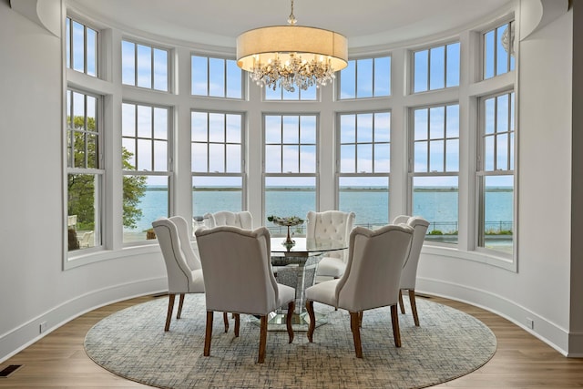25 Brewster Ln, East Setauket, NY 11733 - dining space with a water view, a chandelier, baseboards, wood finished floors, and a towering ceiling
