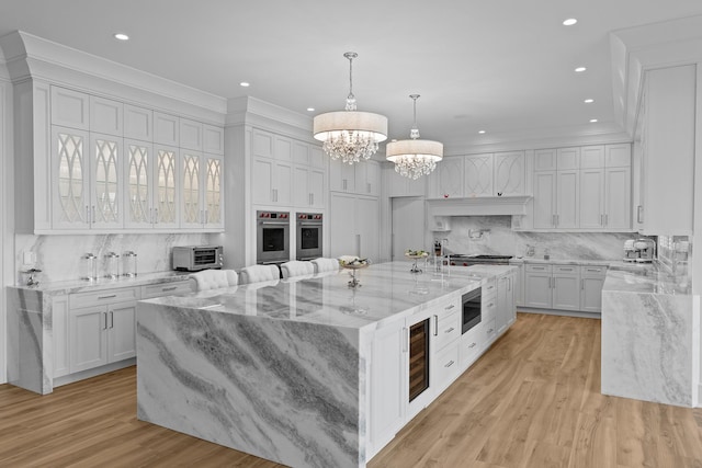 25 Brewster Ln, East Setauket, NY 11733 - kitchen with appliances with stainless steel finishes, a chandelier, wine cooler, backsplash, and white cabinetry