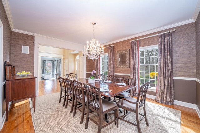 dining area featuring light wood-type flooring, baseboards, a notable chandelier, and ornamental molding