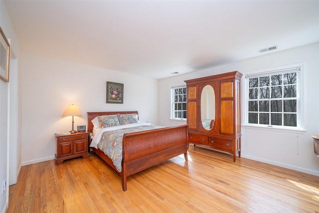 bedroom with baseboards, multiple windows, light wood-style floors, and visible vents
