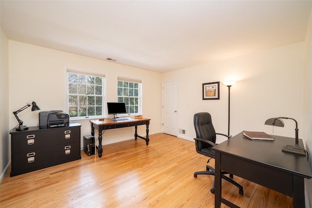 office featuring baseboards, light wood-style flooring, and visible vents