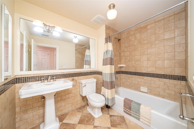 bathroom with tile walls, shower / tub combo with curtain, visible vents, and toilet